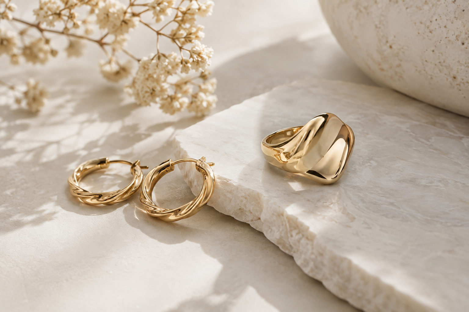 Gold jewellery arranged on an ivory texture surface